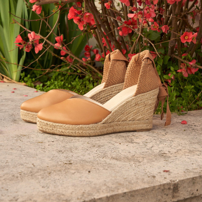 Elba wedge espadrille in camel leather, angled view, on a floral edge - MONPIEL
