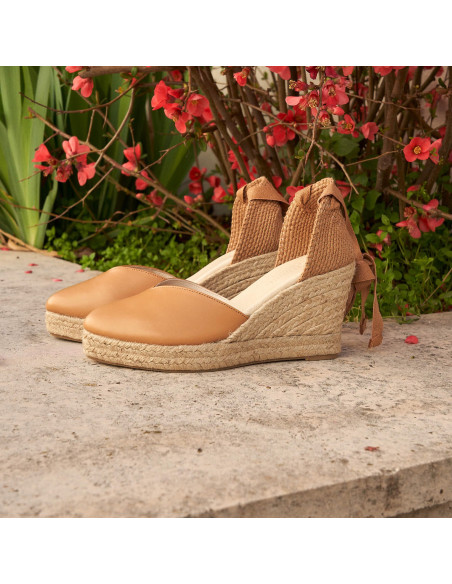Espadrille à talon compensé Elba en cuir camel, vue en perspective sur une bordure fleurie - MONPIEL