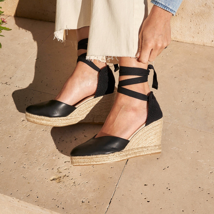 Elba wedge espadrille in black leather, feet tilted on the ground, side view of the espadrilles - MONPIEL