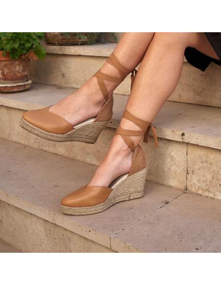 Espadrille à talon compensé Elba en cuir camel, jambes croisées sur des escaliers - MONPIEL