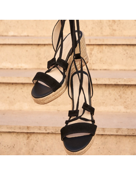 Schwarze Ledersandalen mit Keilabsatz und Riemen, hängend vor einem Hintergrund im Freien - MONPIEL Schwarze Ledersandalen mit Keilabsatz und Riemen, hängend vor einem Hintergrund im Freien - MONPIEL