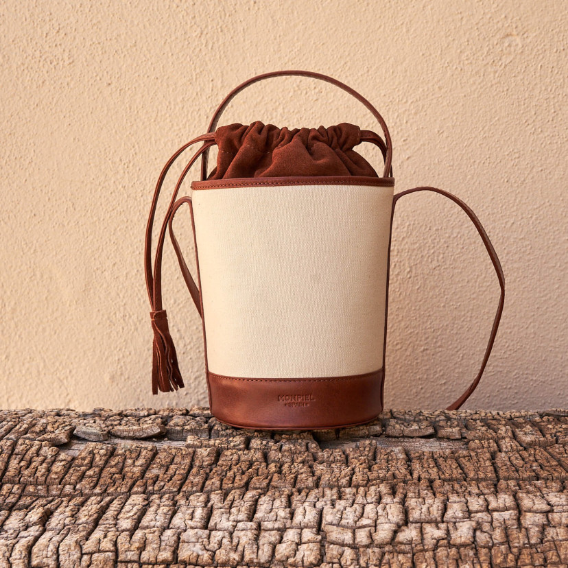 Bolsa cubo pequena de canvas em tom couro com vista frontal apoiada em tronco - MONPIEL