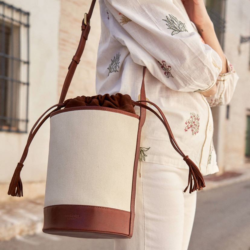 Bolsa cubo de canvas e couro em tom couro pendurada no ombro ao ar livre - MONPIEL