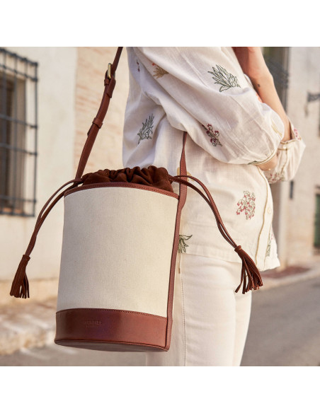 Borsa a secchiello in canvas e pelle color cuoio, indossata sulla spalla all’esterno - MONPIEL