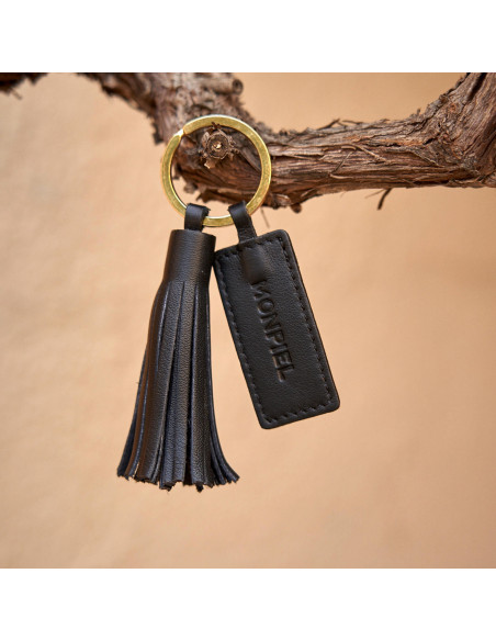 Chaveiro de borla de couro preto com detalhe de logo, pendurado em um galho - MONPIEL Chaveiro de borla de couro preto com detalhe de logo, pendurado em um galho - MONPIEL
