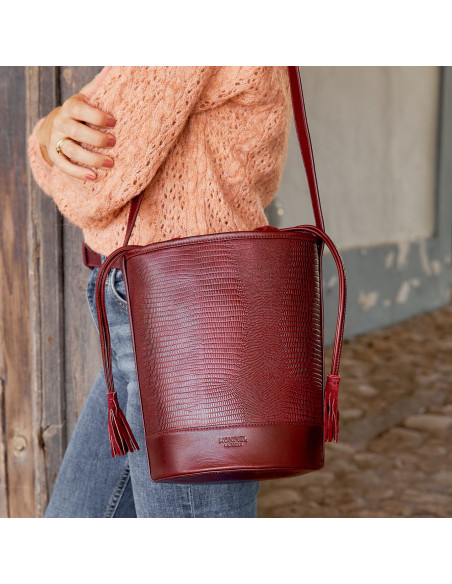 Bolso redondo en forma de cubo de piel en color serpiente burdeos colgado al hombro con vista frontal - MONPIEL