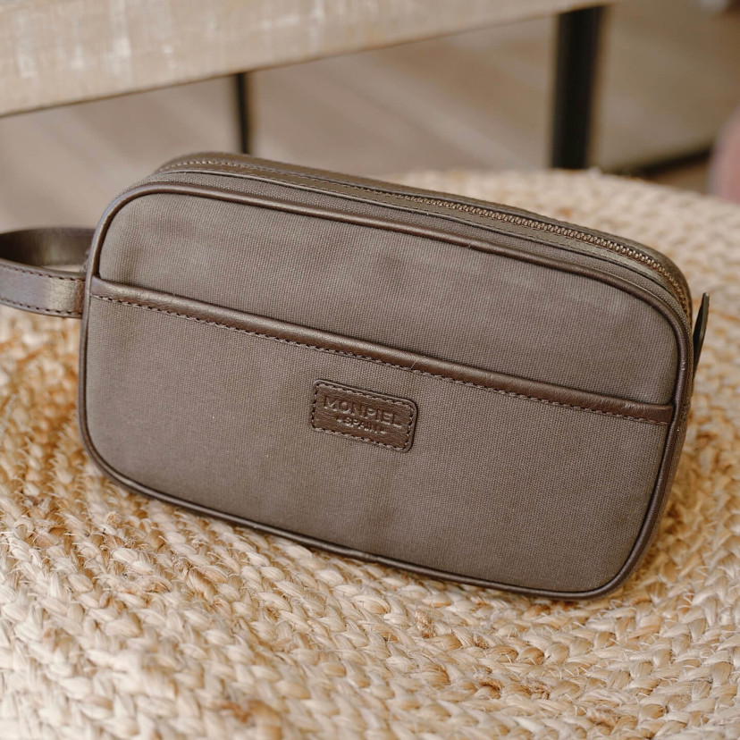 Necessaire masculino de canvas e couro em verde, com vista frontal apoiado sobre esparto - MONPIEL