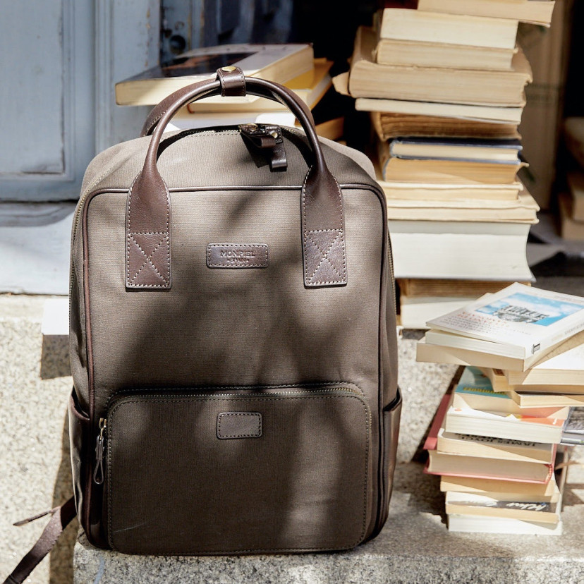 Sport canvas and leather backpack in green color, front view, next to books - MONPIEL