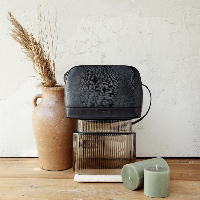 Medium leather bag in black snakeskin pattern, front view, on top of a vase - MONPIEL