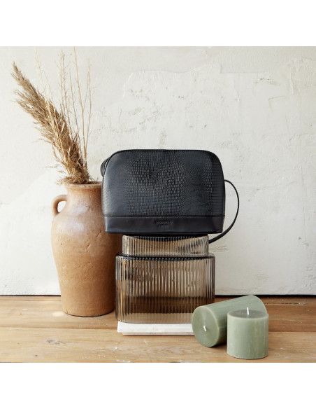 Medium leather bag in black snakeskin pattern, front view, on top of a vase - MONPIEL Medium leather bag in black snakeskin pattern, front view, on top of a vase - MONPIEL