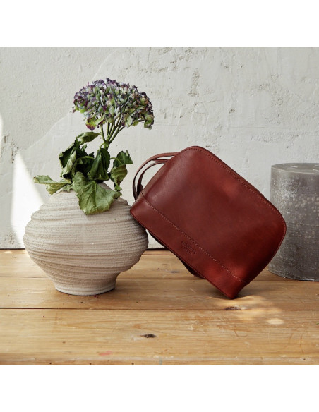 Borsa media in pelle color cuoio, vista frontale, inclinata su un vaso - MONPIEL