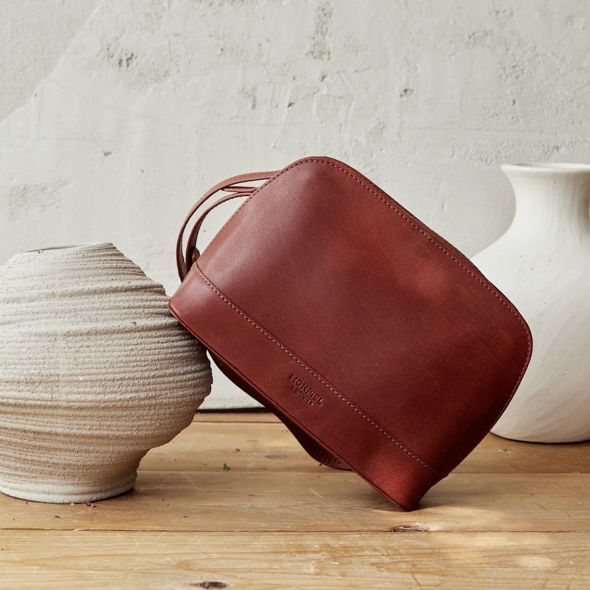 Medium leather bag in tan color, front view, tilted on a vase, close-up - MONPIEL