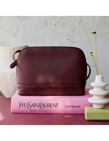 Medium leather bag in burgundy snakeskin pattern, front view, resting on a book - MONPIEL Medium leather bag in burgundy snakeskin pattern, front view, resting on a book - MONPIEL