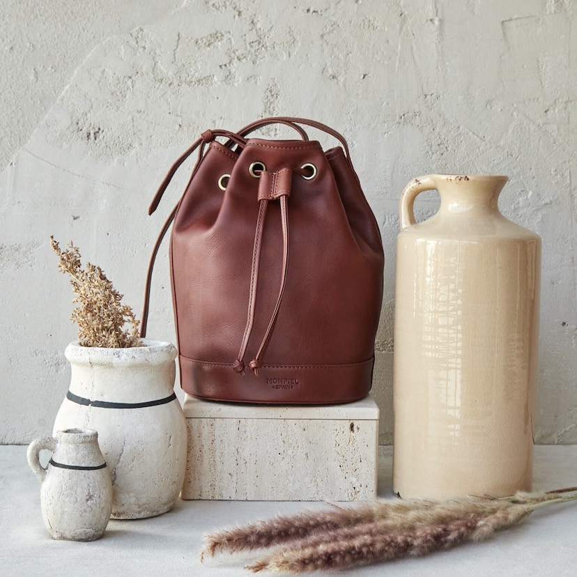 Large leather bucket bag in tan color, front view, beside vases - MONPIEL