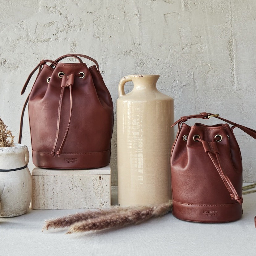Large leather bucket bag in tan color, front view with a small bag, vase in between - MONPIEL