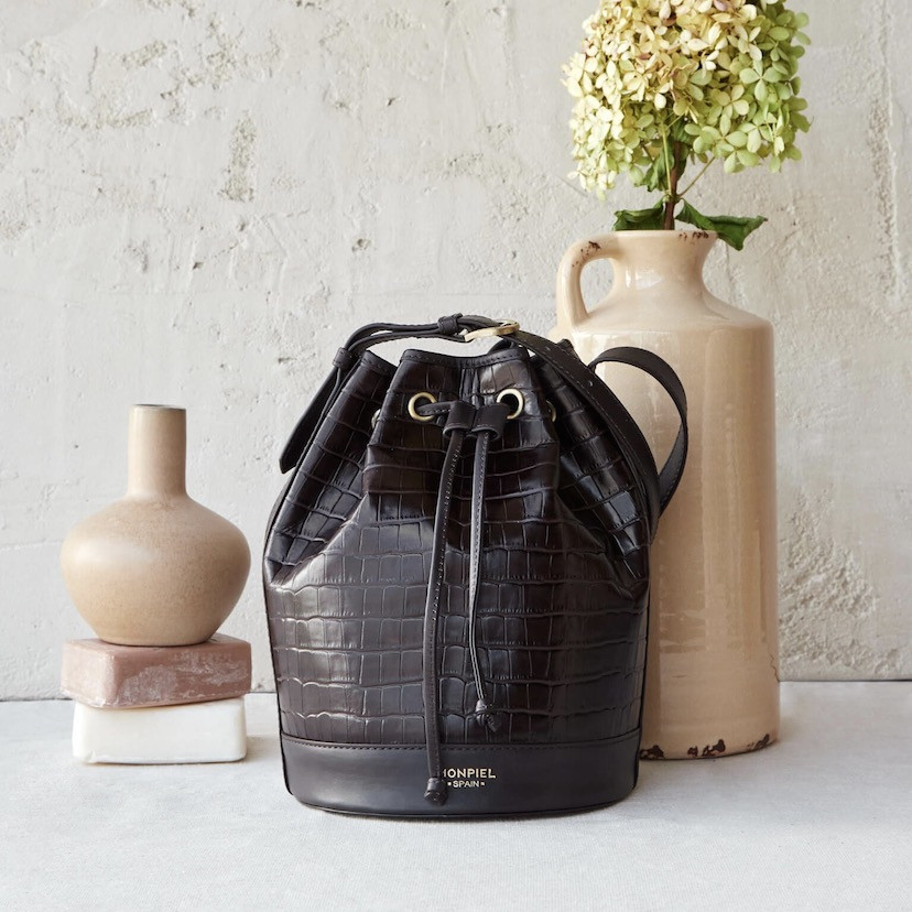 Large crocodile-patterned leather bucket bag in brown color, front view, in front of a vase - MONPIEL