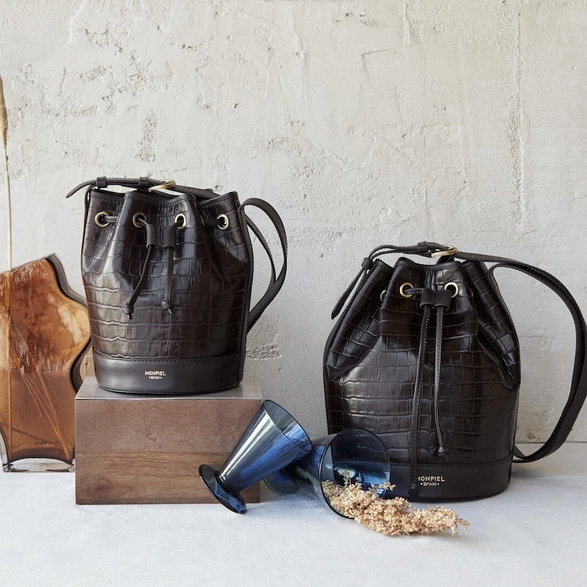 Large crocodile-patterned leather bucket bag in brown color, with a small bag beside it - MONPIEL