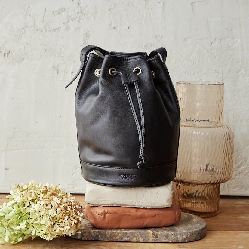Large black leather bucket bag, front view, in front of a vase - MONPIEL