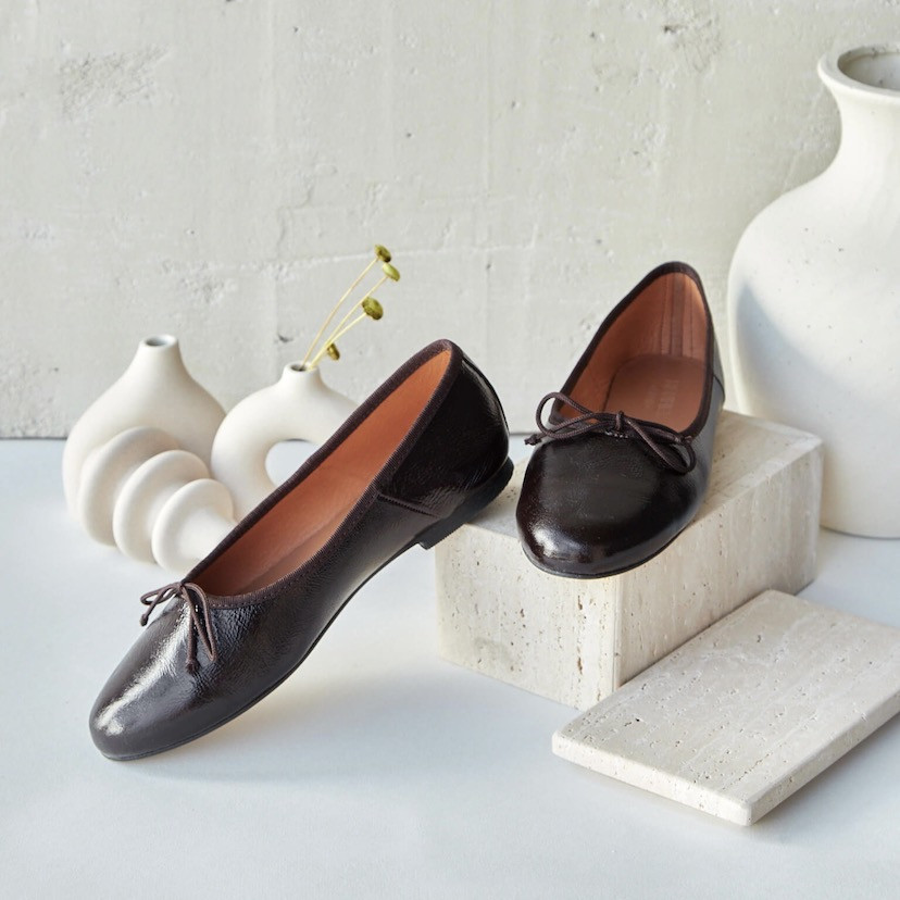 High-cut patent leather ballerina in brown color, angled view, heel resting with vases - MONPIEL