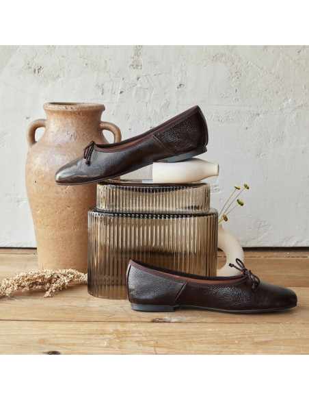 High-cut patent leather ballerina in brown color, side view, ballerina resting on vases - MONPIEL High-cut patent leather ballerina in brown color, side view, ballerina resting on vases - MONPIEL