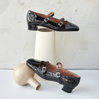Lolina patent leather Mary Janes in black color, side and angled views, resting on a vase - MONPIEL 2