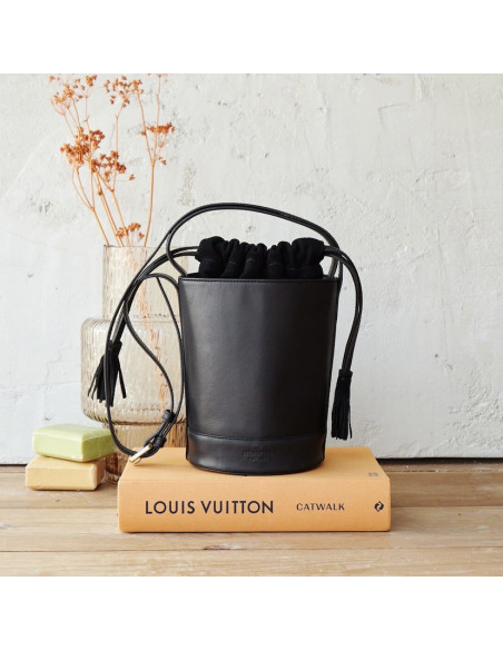 Petit sac seau rond en cuir noir, vue de face, posé sur un livre - MONPIEL