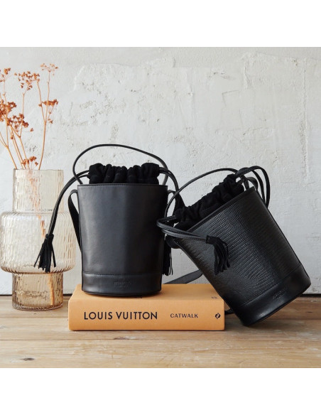 Petit sac seau rond en cuir noir posé sur un livre avec un petit sac seau en cuir motif serpent noir également posé - MONPIEL