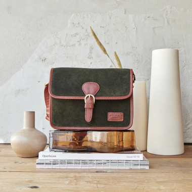 Black suede satchel bag with buckle, front view, resting on books - MONPIEL 2