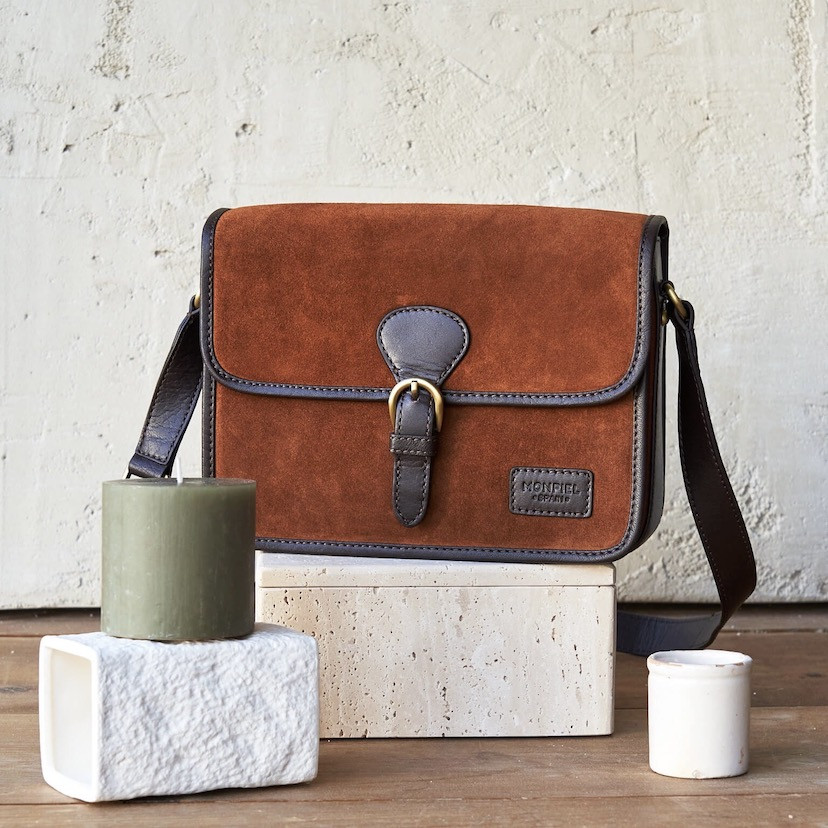 Bolsa satchel com fivela em serraje cor de couro, vista frontal apoiada em pedra - MONPIEL