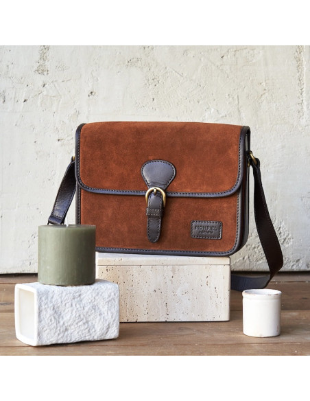 Borsa satchel con fibbia in pelle scamosciata color cuoio, vista frontale, appoggiata su pietra - MONPIEL