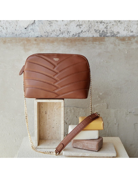Tan quilted leather bag with a gold chain, next to soaps - MONPIEL