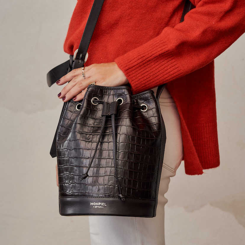 Large brown coco leather bucket bag with front view, hanging from the shoulder with hand resting - MONPIEL