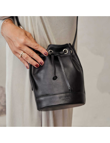 Bolso saco bombonera pequeño de piel en color negro con vista frontal con detalle mano - MONPIEL Bolso saco bombonera pequeño de piel en color negro con vista frontal con detalle mano - MONPIEL