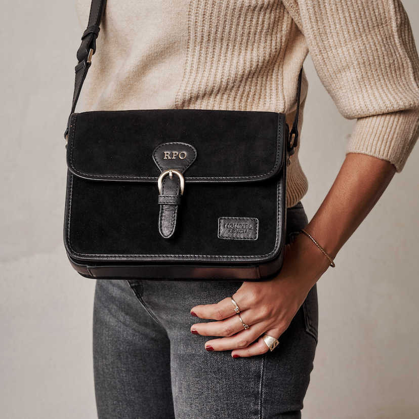 Bolsa satchel em camurça preta com fivela, vista frontal, usada na bandoleira, detalhe das iniciais personalizadas - MONPIEL