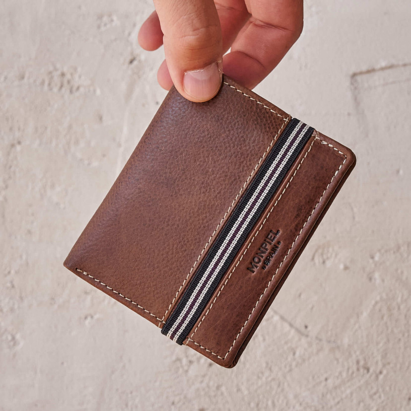 Brown leather wallet with coin purse and rubber detail, front view, held by hand - MONPIEL