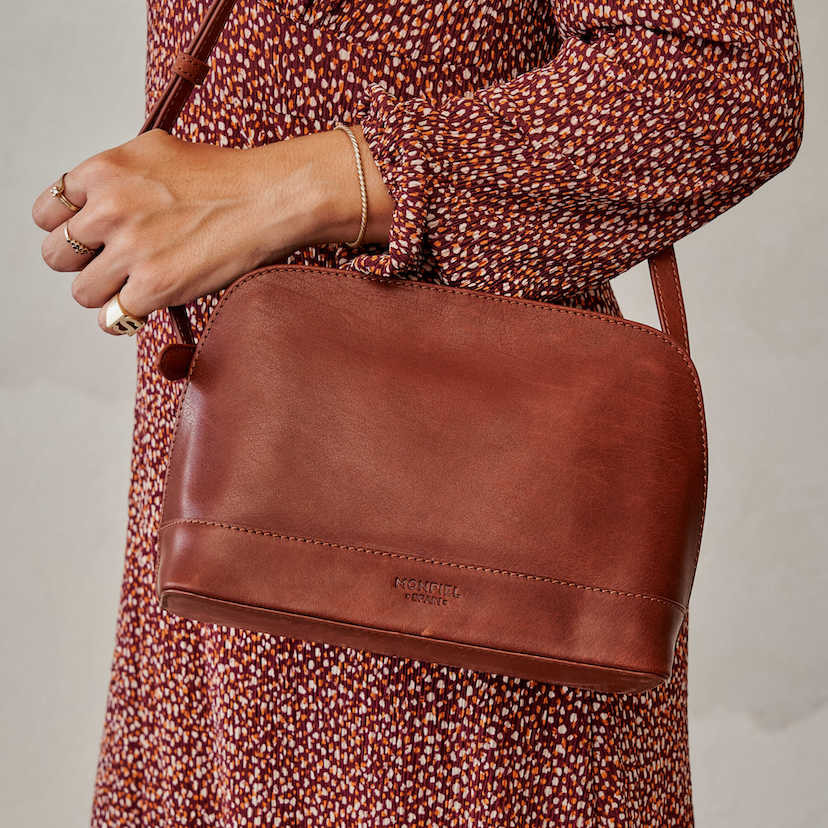 Medium leather bag in leather color, hanging from the shoulder, paired with a dress - MONPIEL