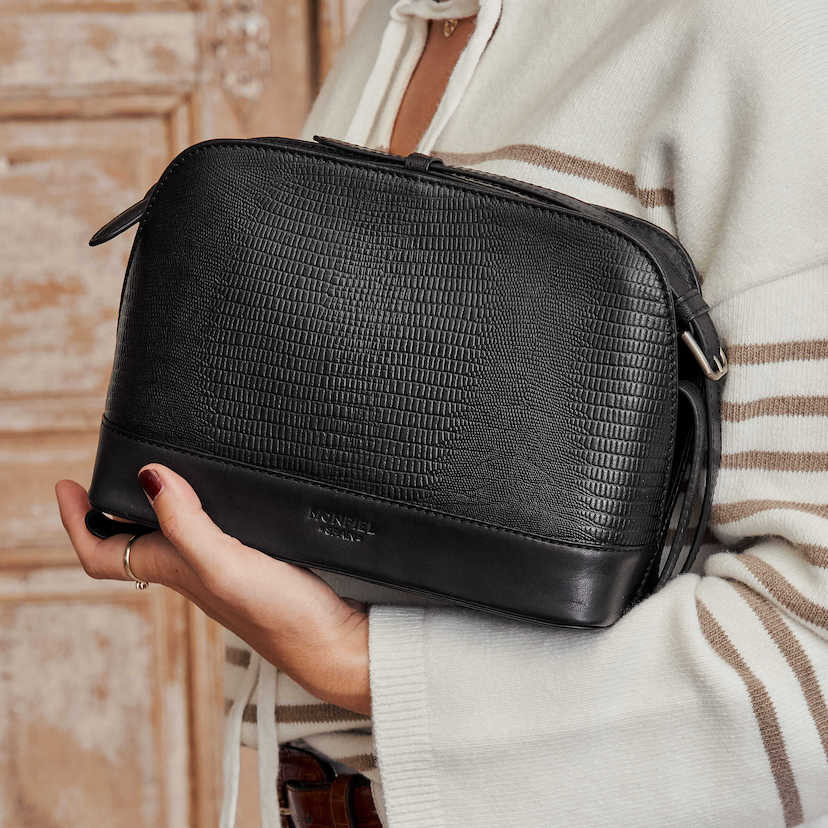 Bolsa média de couro preta com estampa de cobra, vista frontal, apoiada no braço - MONPIEL