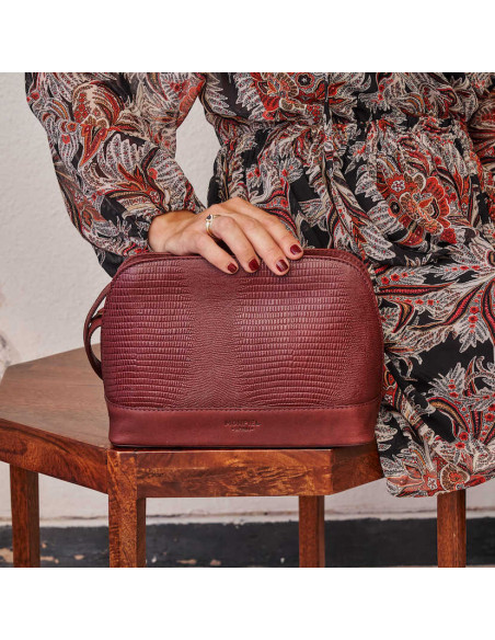 Bolsa média de couro bordô com estampa de cobra, vista frontal, apoiada na mesinha - MONPIEL Bolsa média de couro bordô com estampa de cobra, vista frontal, apoiada na mesinha - MONPIEL