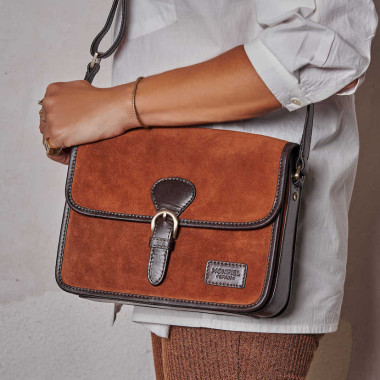 Bolsa satchel com fivela em camurça preta, vista frontal apoiada em livros - MONPIEL 2