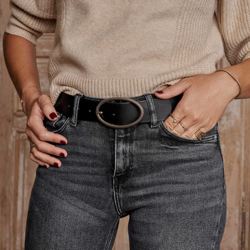 Cinto de couro preto com fivela oval, vista frontal, sobre jeans - MONPIEL