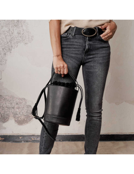 Black leather belt with an oval buckle, mid-shot, holding a black leather bag - MONPIEL