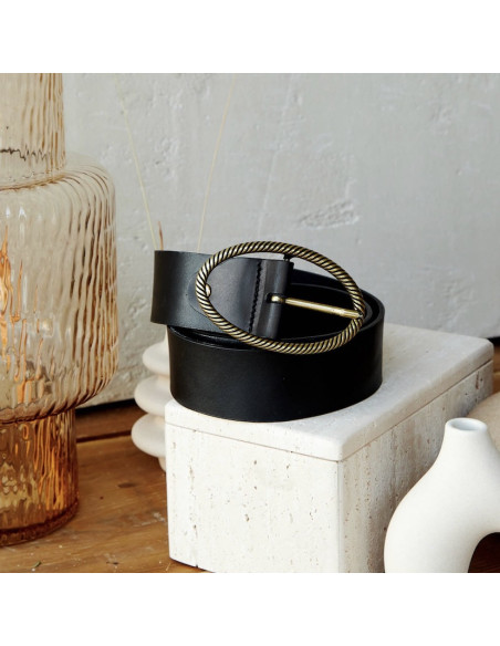 Black leather belt with an oval buckle, coiled next to a vase - MONPIEL