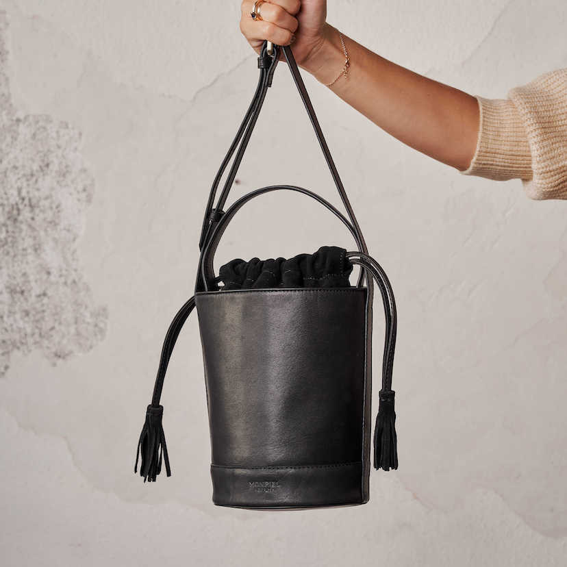 Bolsa redonda pequena de couro preto com alça pendurada, vista frontal - MONPIEL