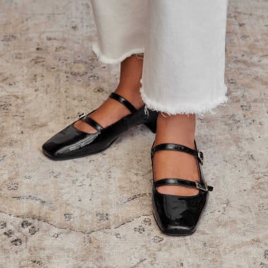 Lolina patent leather Mary Janes in black color, side and angled views, resting on a vase - MONPIEL 2