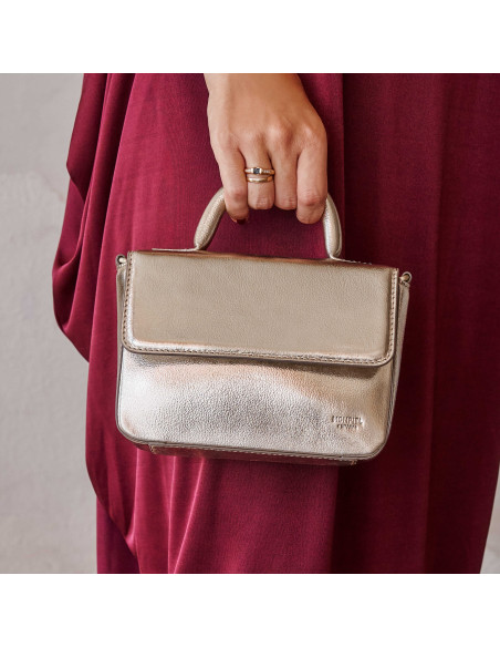 Bolsa pequena de couro metálico champanhe, vista frontal, segurada pela alça - MONPIEL Bolsa pequena de couro metálico champanhe, vista frontal, segurada pela alça - MONPIEL