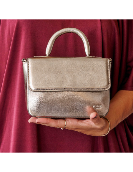 Bolsa pequena de couro metálico champanhe, vista frontal, apoiada na mão - MONPIEL Bolsa pequena de couro metálico champanhe, vista frontal, apoiada na mão - MONPIEL
