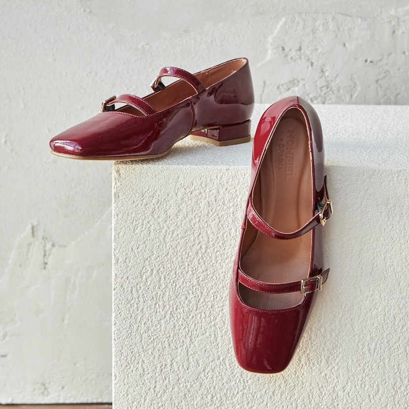 Burgundy patent leather Lolina low-heeled Mary Janes, resting on a stone cube - MONPIEL