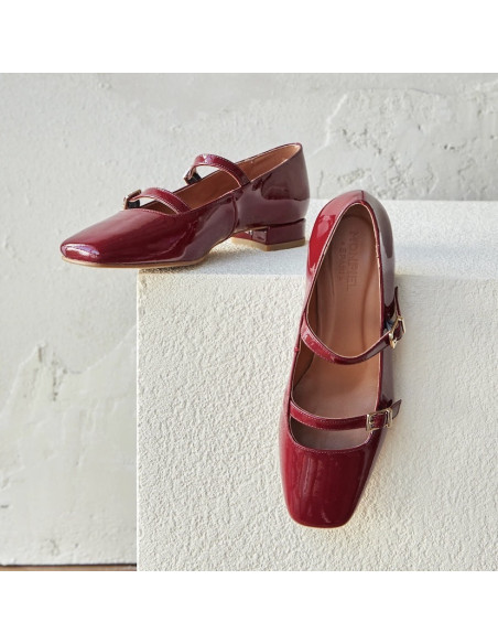 Low-heeled patent leather Mary Janes in burgundy, resting on a stone cube - MONPIEL Low-heeled patent leather Mary Janes in burgundy, resting on a stone cube - MONPIEL