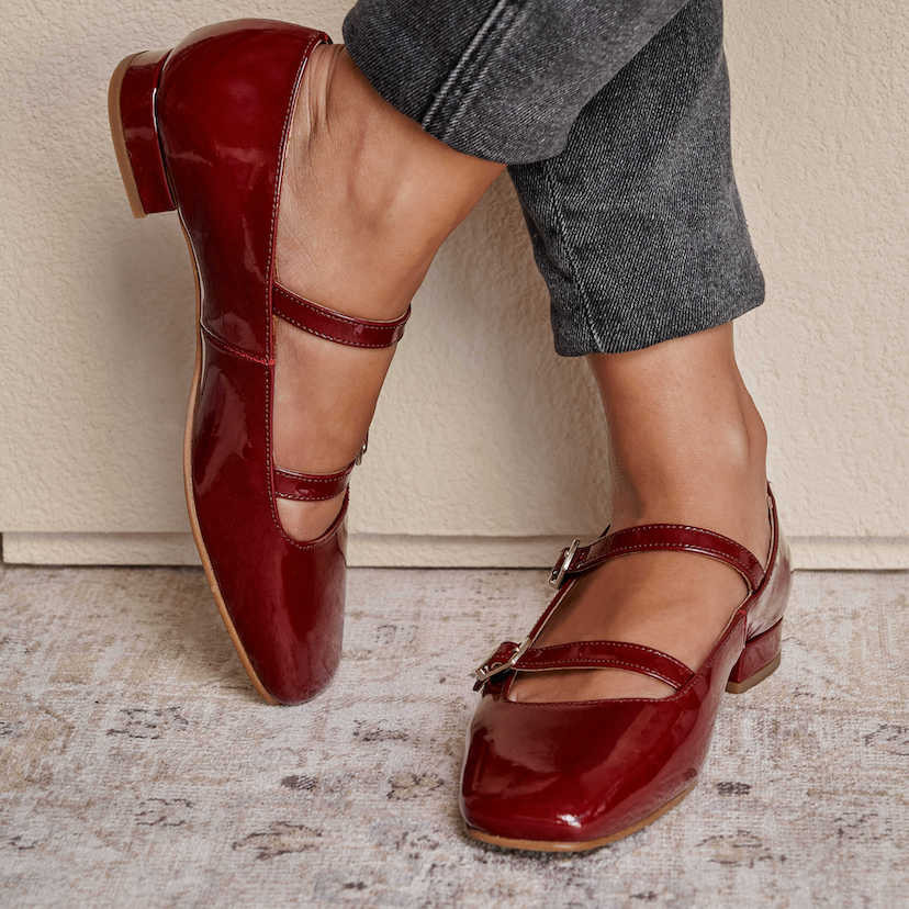 Burgundy patent leather Lolina low-heeled Mary Janes, feet crossed, resting against the wall - MONPIEL