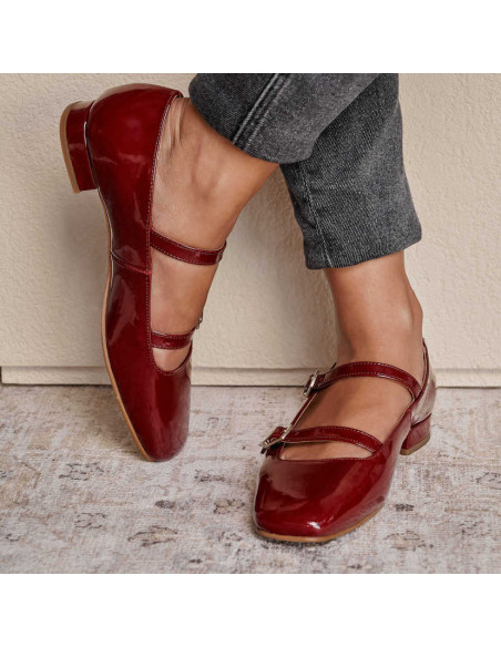 Low-heeled patent leather Mary Janes in burgundy, crossed feet resting against the wall - MONPIEL Low-heeled patent leather Mary Janes in burgundy, crossed feet resting against the wall - MONPIEL
